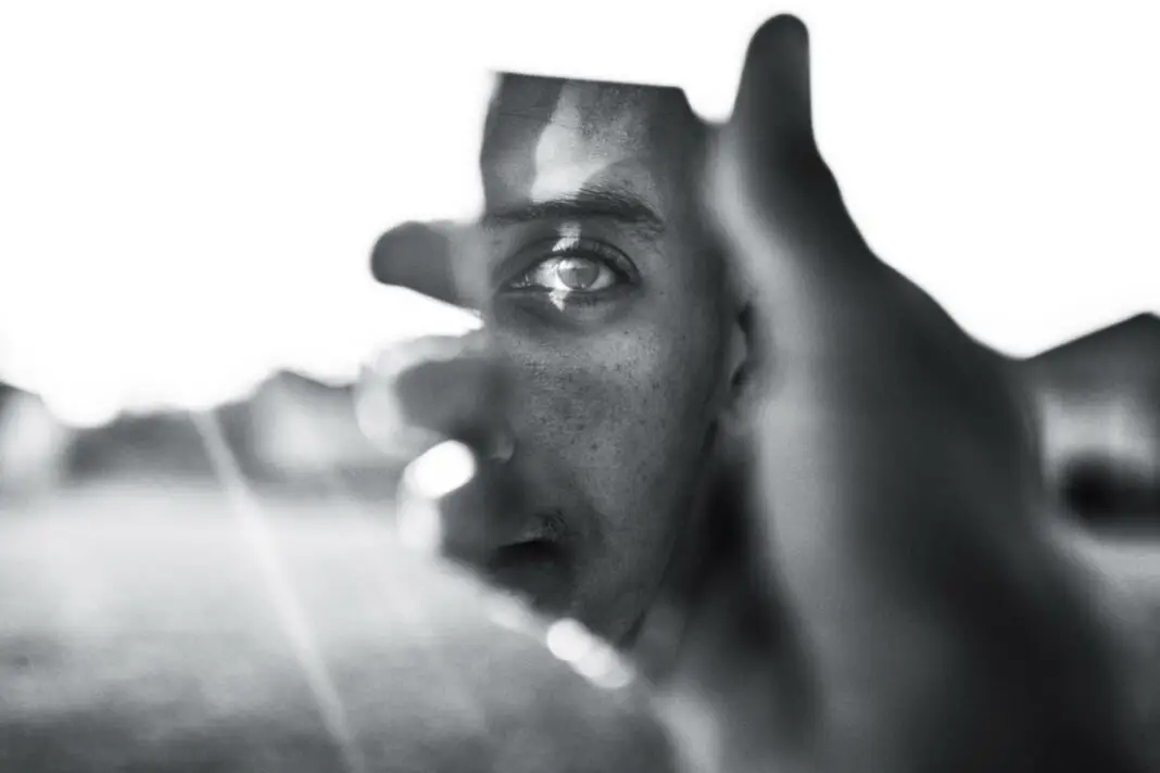 A face seen through a gap in a hand held up to the camera